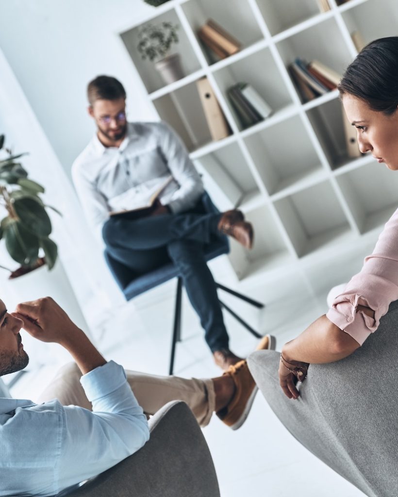 Helping others. Young married couple talking while sitting on the therapy session with psychologist